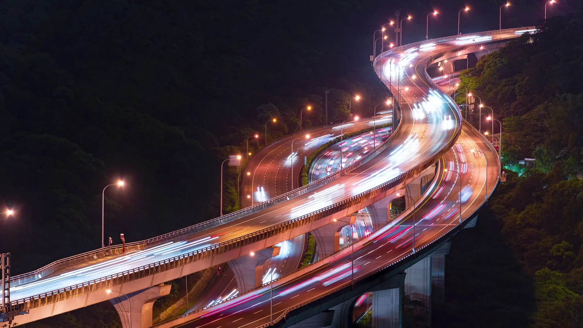 Elevated highway interchange at night with traffic light trails